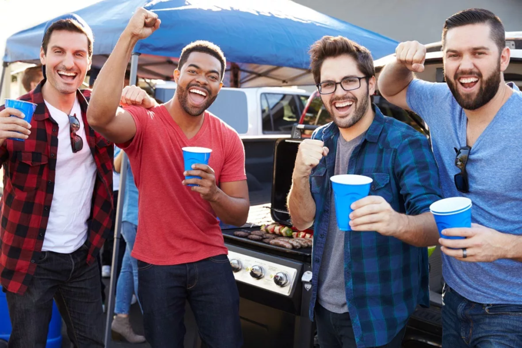 Friends wearing casual gear apparel while using a soft cooler at a tailgate party