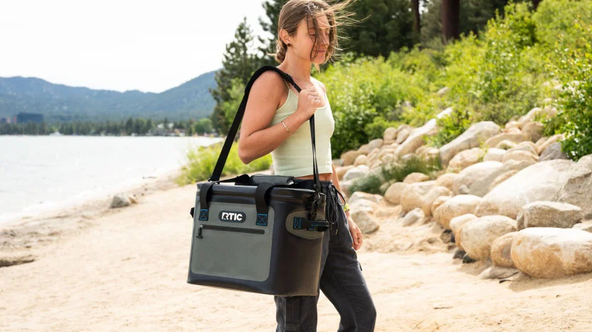 Person carrying a portable insulated bag while hiking to show how do i choose the right size soft cooler for my needs.