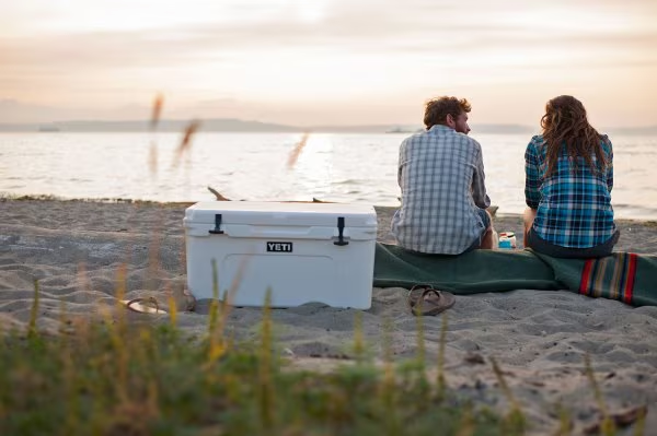 Beige YETI cooler rugged storage solution sitting on a truck bed at a scenic campsite